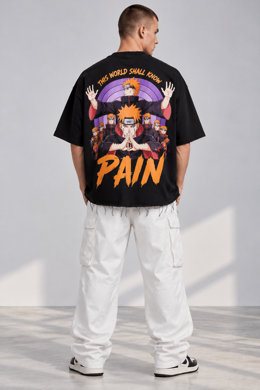Back studio model mockup of black oversized Pain anime T-shirt with large purple and orange back graphic and distressed hem